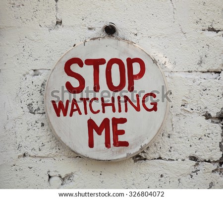 Stop Watching Me sign hanging on wall