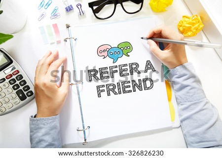 Person drawing Refer A Friend concept on white paper in the office
