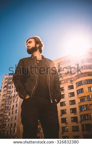 Low angle shot of young guy, standing in the urban block.
