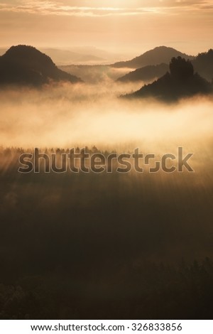 Distant mountain range and heavy clouds of colorful  mist above deep valleys