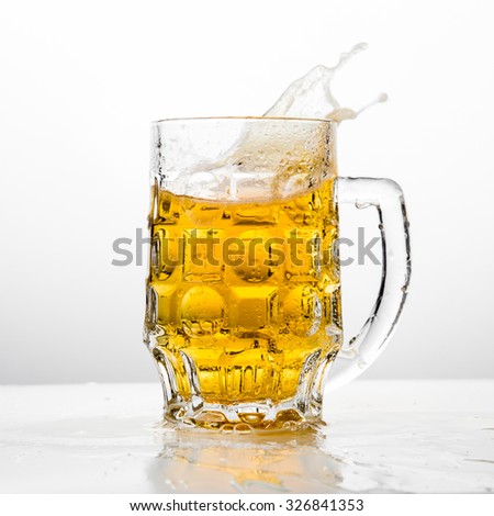 Beer splashing in glasses on white.