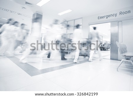 A motion blurred photograph of a patient on stretcher or gurney being pushed at speed through a hospital corridor. Royalty-Free Stock Photo #326842199