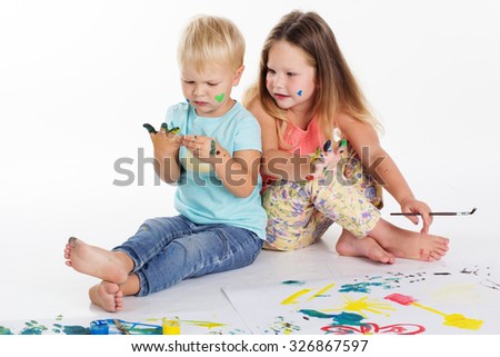 Two pretty child friends boy and girl are drawing pictures by aquarelle paints