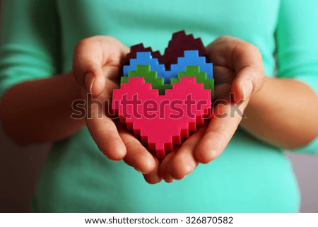 Closeup of plastic puzzle hearts in female hands