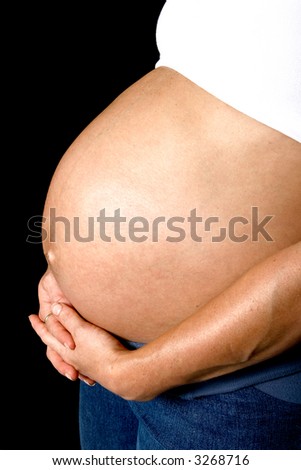 Hands tenderly holding a full rounded pregnant belly, isolated on black.
