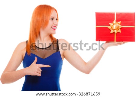 People celebrating holidays, love and happiness concept - smiling red head girl in blue dress holds red gift box pointing studio shot isolated. Time gifts