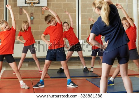 Teacher Taking Exercise Class In School Gym Royalty-Free Stock Photo #326881388