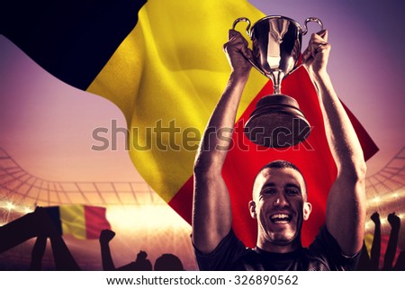 Portrait of successful rugby player holding trophy against large football stadium under purple sky