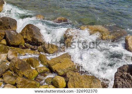 Big wave splash. Sea water beating against the rocks and cliffs. Blue sky above the beach in the sun zenith refreshing drops of water of the ocean. As background for the design of stage