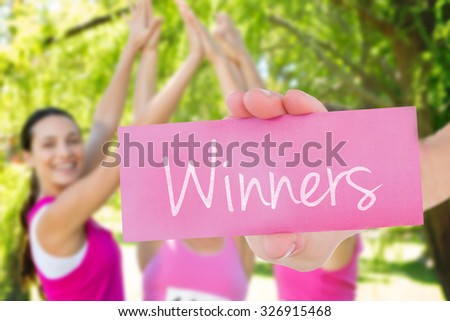 The word winners and young woman holding blank card against smiling women running for breast cancer awareness