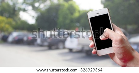 hands holding mobile phone with blur cars parking