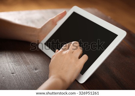the girl behind the tablet on a wooden table