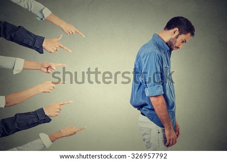 Concept of accusation guilty person guy. Side profile sad upset man looking down many fingers pointing at his back isolated grey office wall background. Negative human face expression emotion feeling Royalty-Free Stock Photo #326957792