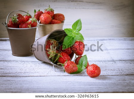 Strawberry in a small bucket on the wooden board. For this photo applied vignetting effect.