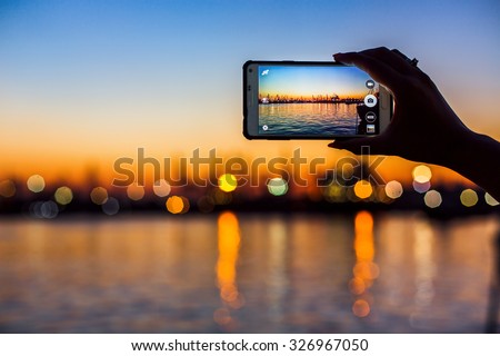 Wonderful sunset over sea harbor, tourist taking a picture of the seaport