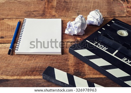 Movie clapper with notepad and pencil on wooden table
