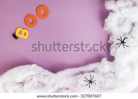 Boo Halloween text in colorful letters over purple background and spider web round, copyspace
