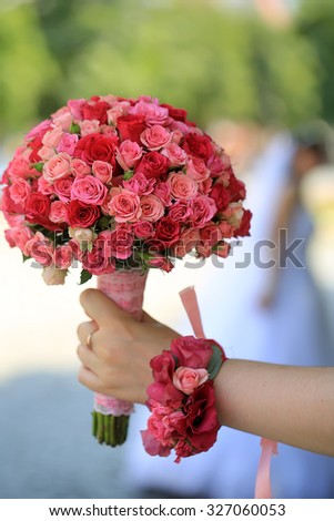 Closeup of female hand holding one big beautiful colorful soft aroma fresh wedding bouquet of many pink and purple rose flowers sunny day outdoor on natural background, vertical picture