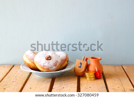 image of jewish holiday Hanukkah with donuts and wooden dreidels (spinning top). retro filtered
