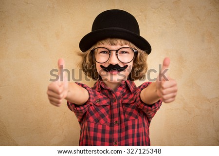 Funny kid with fake mustache. Happy child playing in home  Royalty-Free Stock Photo #327125348