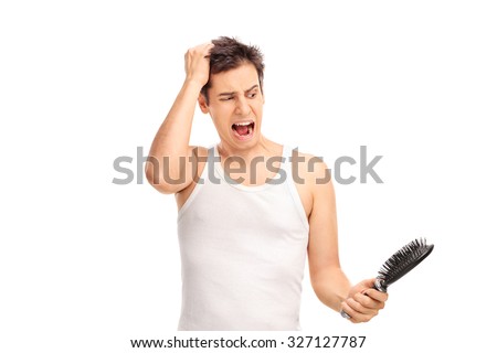 Angry young man loosing hair and holding a hairbrush isolated on white background Royalty-Free Stock Photo #327127787