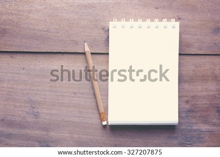 Top view work space notebook and brown pencil on wood table background,retro effect