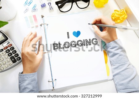  Person drawing I Love Blogging concept on white paper in the office