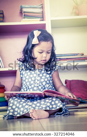 Child read, cute little girl reading a book and sitting on floor,vintage filter