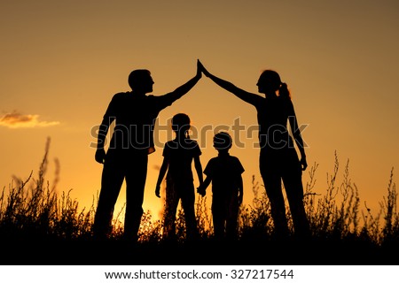 Happy family standing in the park at the sunset time.  Concept of friendly family.