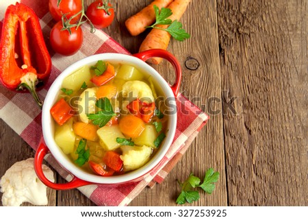 Vegetable soup with ingredients carrot cauliflower potato parsley pepper cabbage tomato over rustic wooden background with copy space Royalty-Free Stock Photo #327253925