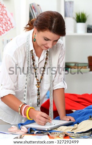 Portrait of adult female dressmaker drawing some clothing design. Woman at work
