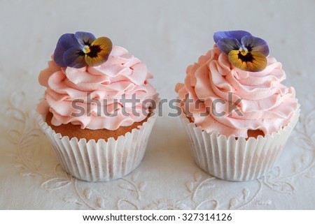 Homemade pink frosting vanilla cupcakes with edible flowers 