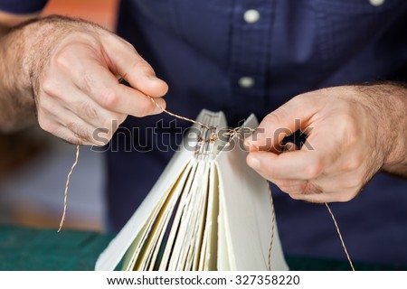 Midsection of male worker binding pages in paper factory Royalty-Free Stock Photo #327358220
