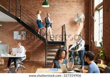 Start of a busy day at work in trendy office with business people Royalty-Free Stock Photo #327359906