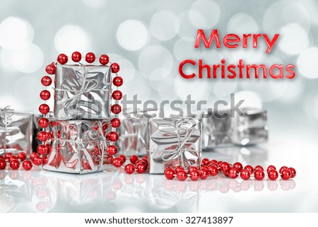 Small Christmas gifts in shiny silver paper and red tinsel beads ornament