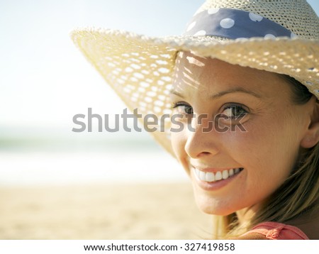 happy girl smiling portrait in the beach  wearing a picture hat with the sea and horizon in the background