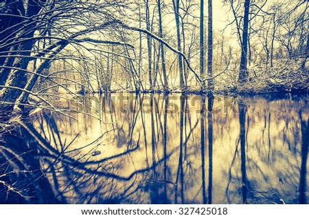 Vintage photo of river in forest at winter. Beautiful winter time photo with vintage mood effect.