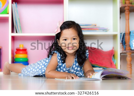 Child read, cute little girl reading a book and lying on floor on bookshelf background