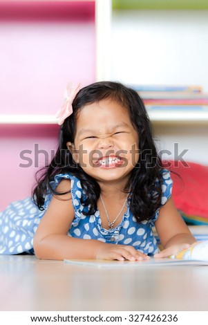 happy cute little girl smiling and lying on floor