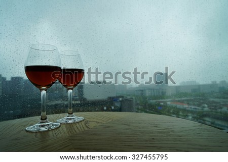 The cups of red wine on a rainy day window background.