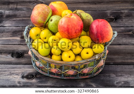 Various fruits in the basket isolated on rustic wood background.