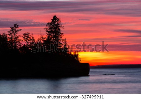 Lake Superior Sunset - A fiery blaze lights the sky from this late day sunset and creates a silhouette of the jack pines on this peninsula. Five Mile Point in the Upper Peninsula of Michigan.