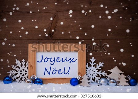 Blue Decoration On Snow. Christmas Tree Balls, Snowflakes And Christmas Tree. Picture Frame. French Text Joyeux Noel Mean Merry Christmas. Rustic, Vintage Brown Wooden Background