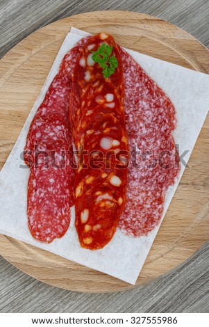 Salami sausage with parsley on the wood background