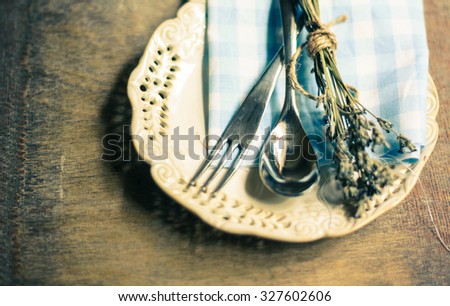 Rustic Table Setting with napkin, silverware and dry lavendre lowers on old wooden table. Toned picture