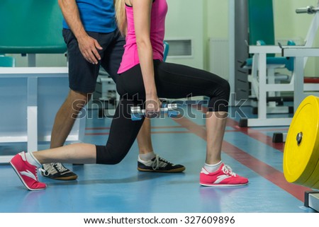 Beautiful girl practicing with a trainer at the gym. Proper physical exercises under the supervision of a trainer. Photos for sporting magazines and websites.
