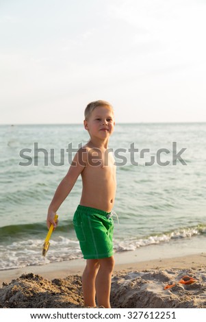 Boy shorts on the beach. Children playing with sea sand. Joy and fun for children. A beautiful warm day. Photo for children's magazines and websites.
