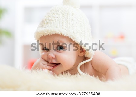 Cute little baby girl looking into the camera and weared in white hat.  Royalty-Free Stock Photo #327635408