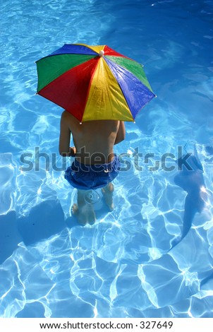 Boy under umbrella in the pool