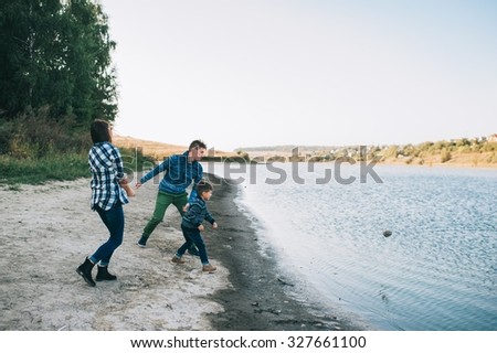 vacation young family near the lake, happy father, mother and son running on beach